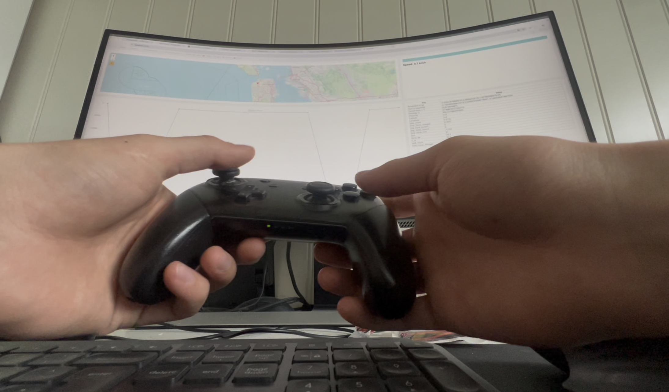POV-bilde av to hender som holder en Nintendo Switch Pro-kontroller foran en krummet skjerm med live navigasjonskart.